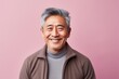 © Leon Waltz - Lifestyle portrait photography of a satisfied Chinese man in his 50s wearing a chic cardigan against a pastel or soft colors background