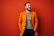 © Eber Braun - Portrait of a happy young man in orange jacket over red background