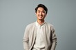 © Anne Schaum - Lifestyle portrait photography of a satisfied Indonesian man in his 20s wearing a chic cardigan against a minimalist or empty room background