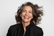 © Robert MEYNER - Lifestyle portrait photography of a happy Brazilian woman in her 50s wearing a sleek suit against a white background