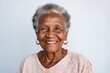 © Anne Schaum - Close-up portrait photography of a pleased 100-year-old elderly Nigerian woman wearing a chic cardigan against a minimalist or empty room background