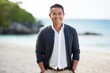 © Anne Schaum - Group portrait photography of a satisfied Indonesian man in his 40s wearing a chic cardigan against a beach background