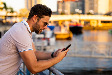 Handsome man chatting on phone on city street. Successful male model talking on phone in big city living the urban lifestyle. Young male fashion model using phone outside. Business phone conversation.