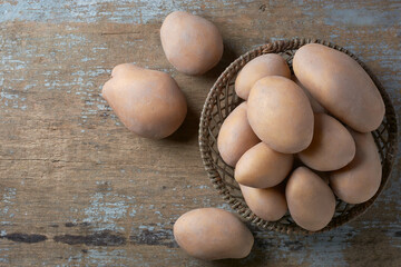 Wall Mural - freshly harvested raw potatoes in a basket, solanum tuberosum, starchy, tuberous vegetables scattered on wooden table top, taken straight from above with copy space