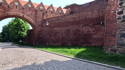 Sticker - Old castle in the city. Building with sky and clouds. A walk through the historic streets in the center of the old town. Old historic street. Torun, Poland.	