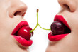 Couple of young female faces with red cherries over white background