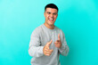 © luismolinero - Young handsome man over isolated blue background pointing to the front and smiling