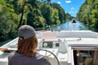 © Iuliia Sokolovska - Family vacation, summer holiday travel on barge boat in canal, young woman by steering wheel on river cruise trip in houseboat
