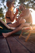 Young couple in swimsuits having fun on vacation. Man and woman sitting on sunbed in front of each other laughing and sharing watermelon fruit. Holiday, togetherness, lifestyle concept.