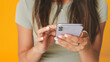 © Andrii Nekrasov - Close-up, hands of unrecognizable girls using phone , isolated over yellow background in studio