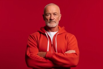 Wall Mural - Medium shot portrait photography of a glad mature man wearing a comfortable tracksuit against a red background. With generative AI technology