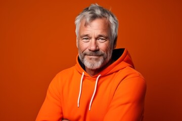 Wall Mural - Medium shot portrait photography of a satisfied mature man wearing a comfortable hoodie against a bright orange background. With generative AI technology