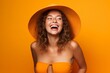 © Markus Schröder - Lifestyle portrait photography of a happy girl in her 20s wearing a daring bikini against a bright orange background. With generative AI technology
