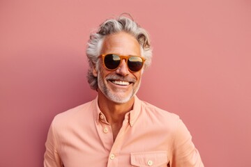 Wall Mural - Medium shot portrait photography of a joyful mature man wearing a trendy sunglasses against a peachy pink background. With generative AI technology