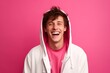 © Markus Schröder - Medium shot portrait photography of a happy boy in his 20s wearing a cozy zip-up hoodie against a hot pink background. With generative AI technology