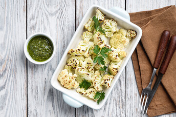 Wall Mural - Roasted white cauliflower with pesto sauce on rustic wooden table