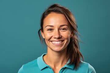 Wall Mural - Headshot portrait photography of a happy girl in her 30s wearing a sporty polo shirt against a teal blue background. With generative AI technology