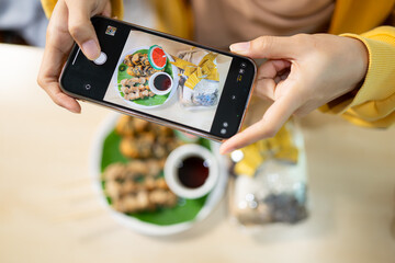 Woman taking photo of mushroom food with smartphone at table in healthy restaurant