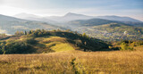 Fototapeta Na ścianę - Foggy summer landscape with green rural field in the Alps with beautiful fresh green mountain pastures and mountain tops in the background. Rich harvest concept. Creative image. Carpathian mountains