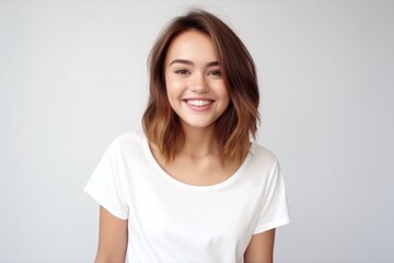 Medium shot portrait photography of a glad girl in her 20s wearing a casual t-shirt against a pearl white background. With generative AI technology