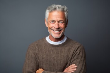 Wall Mural - Lifestyle portrait photography of a grinning mature man wearing a cozy sweater against a cool gray background. With generative AI technology