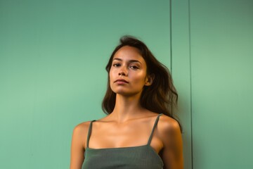 Wall Mural - Lifestyle portrait photography of a glad girl in her 30s wearing a daring tube top against a spearmint green background. With generative AI technology