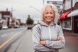 © Markus Schröder - Casual fashion portrait photography of a grinning mature girl wearing a comfortable tracksuit against a small town main street background. With generative AI technology