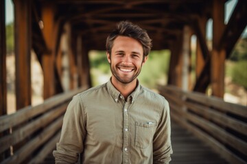 Wall Mural - Close-up portrait photography of a satisfied boy in his 30s wearing a classy button-up shirt against a rustic bridge background. With generative AI technology