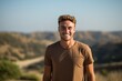 © Markus Schröder - Sports portrait photography of a happy boy in his 30s wearing a casual t-shirt against a rolling hills background. With generative AI technology
