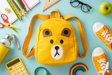 Nurturing Bright Minds. Overhead Shot Of A Yellow Child's Rucksack With Cartoon Bear Print Packed With Assorted Colorful School Materials And Pair Of Shoes On A Soft Blue Background