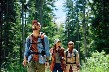 happy backpacker and his friends hiking in forest.