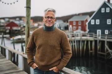 Wall Mural - Eclectic portrait photography of a satisfied mature man wearing a cozy sweater against a picturesque fishing village background. With generative AI technology
