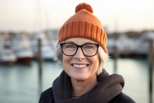 Studio Portrait Photography Of A Happy Mature Girl Wearing A Warm Beanie Or Knit Hat Against A Busy Marina Background. With Generative AI Technology