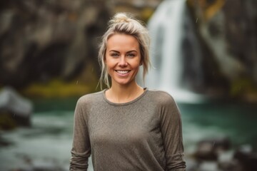Wall Mural - Close-up portrait photography of a happy girl in her 30s wearing a versatile pair of leggings against a picturesque waterfall background. With generative AI technology
