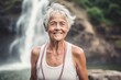 © Markus Schröder - Sports portrait photography of a glad old woman wearing a stylish tank top against a picturesque waterfall background. With generative AI technology