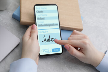 Electronic signature. Woman using mobile phone at table, closeup