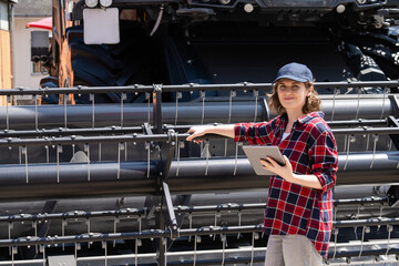 Fototapete - Woman farmer with digital tablet on a background of harvester. Smart farming concept