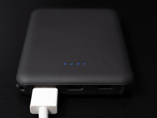 Power bank for charging mobile devices on a black background. Smartphone charger with power supply. External battery for mobile devices.