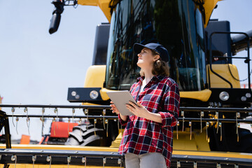 Fototapete - Woman farmer with digital tablet on a background of harvester. Smart farming concept