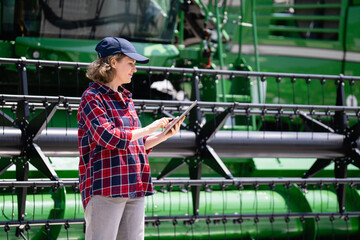 Fototapete - Woman farmer with digital tablet on a background of harvester. Smart farming concept
