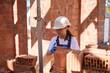 Woman bricklayer in hardhat and building uniform sorting bricks