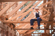 © Viacheslav Yakobchuk - Cheerful high-qualified woman roofer sitting on wooden girder