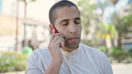 Wall Mural - Young hispanic man speaking on the phone at park