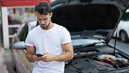 Wall Mural - Young hispanic man texting to insurance for car breakdown at street