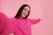 © New Africa - Smiling young woman taking selfie on pink background, space for text
