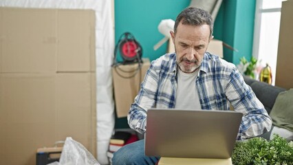 Sticker - Middle age man using laptop sitting on sofa at new home