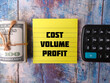 Sticky note and banknotes with the word COST VOLUME PROFIT