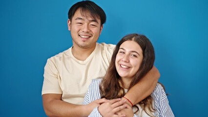 Poster - Man and woman couple smiling confident hugging each other over isolated blue background