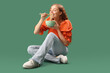 Young woman eating Chinese noodles on green background