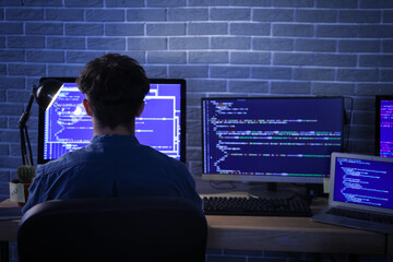 Male programmer working with computer in office at night